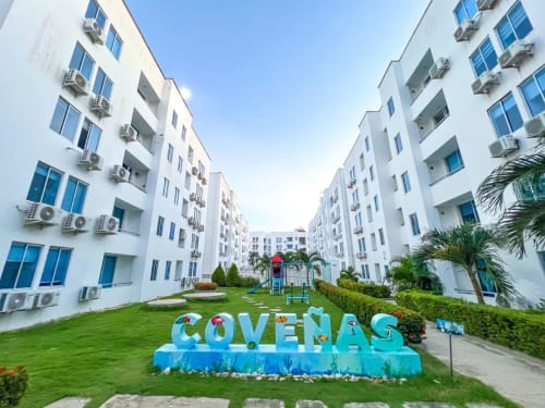 Complejo residencial Olamar en Coveñas con edificios blancos, patio verde y letrero azul COVEÑAS