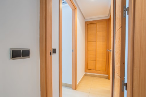 Pasillo moderno del apartamento en Los Alcázares con puertas de madera y suelo de baldosa clara