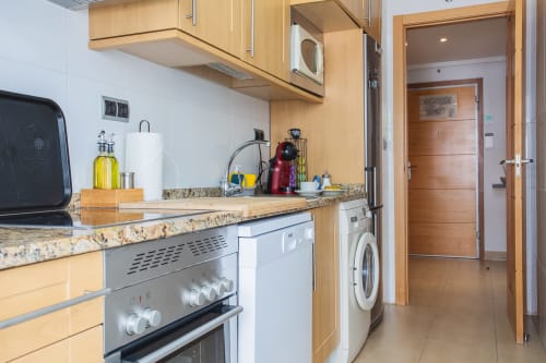 Cocina moderna con encimera de granito, estufa y lavadora en el apartamento El Aljibe de Los Alcázares