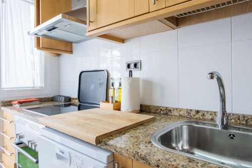 Cocina moderna con encimeras de granito, muebles de madera y fregadero de acero inoxidable en Haus Holiday Homes, Los Alcázares