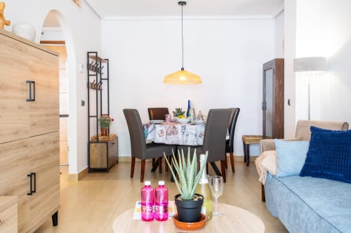 Moderna sala de estar con mesa de comedor, sofá azul y lámpara colgante en Haus Holiday Homes, Los Alcázares
