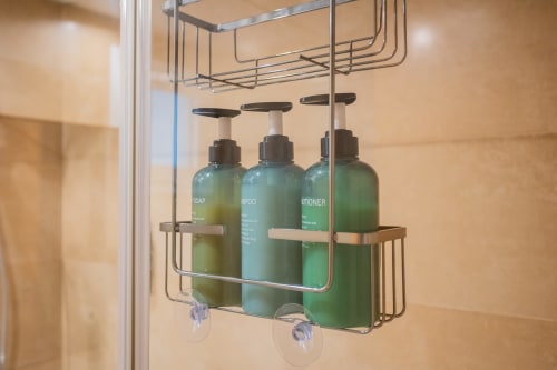 Estantería de ducha con botellas de jabón, champú y acondicionador verdes en el baño del apartamento de Haus Holiday Homes, Los Alcázares