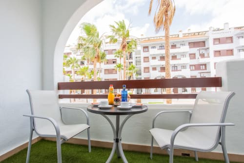 Zona de estar en balcón del apartamento Haus Holiday Homes en Los Alcázares con vistas a palmeras y piscina