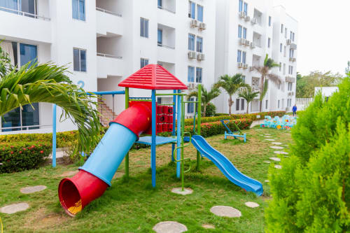 Colorido parque infantil con estructura de toboganes rojo y azul en el complejo de apartamentos Olamar Living en Coveñas, Colombia