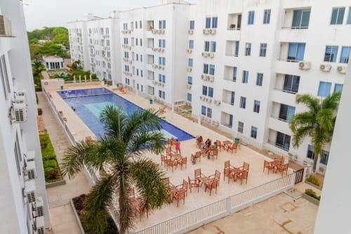 Resort Olamar Living en Santiago de Tolú con edificios blancos, piscina azul, palmeras y terraza amueblada