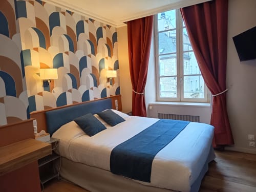 Chambre d'hôtel moderne au Pavillon Saint Martin avec papier peint géométrique, lit queen-size, rideaux bordeaux et parquet