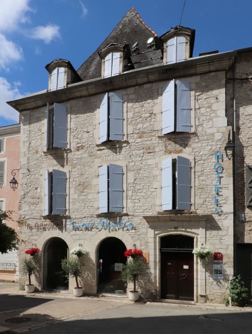 Façade en pierre de l'Hôtel Le Pavillon Saint Martin à Souillac avec fenêtres volets et entrée en arc