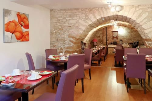 Élégante salle à manger de l'Hôtel Le Pavillon Saint Martin à Souillac avec voûtes en pierre, chaises bordeaux et œuvres d'art contemporain.
