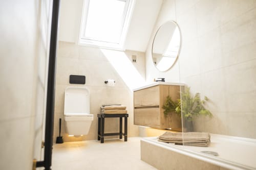 Modern bathroom in The Oriel Loft apartment at Stay at Wellington Circus, Nottingham, featuring white toilet, round mirror,