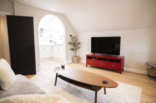 Modern loft apartment living room at Stay Wellington Circus, Nottingham, featuring red TV stand, wooden coffee table, and