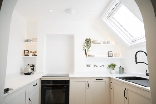 Modern white kitchen in The Oriel Loft apartment at Wellington Circus, Nottingham, featuring built-in appliances and skylight