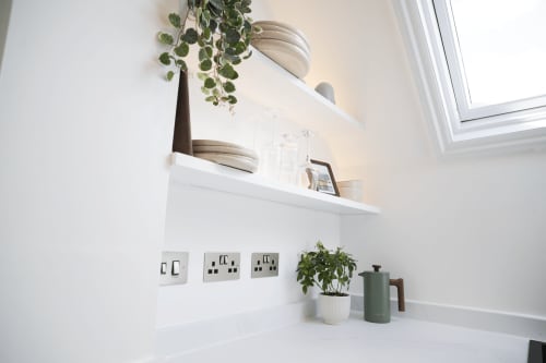 Modern kitchen shelf in The Oriel Loft, Nottingham, with white floating shelf, potted plants, green kettle, and electrical
