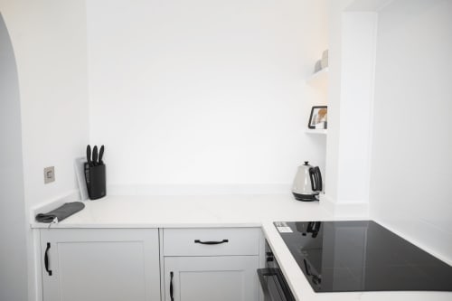 Modern white kitchen corner in The Oriel Loft, Wellington Circus Nottingham, featuring black induction hob, knife block, and