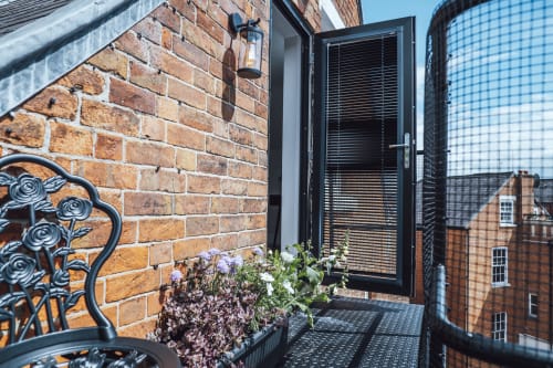 Modern black door with louvered panels on red brick building at Stay at Wellington Circus, Nottingham apartment