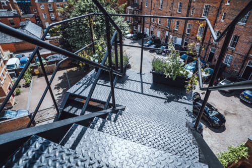 Metal staircase with diamond plate steps leading to rooftop terrace at The Oriel Loft apartment in Nottingham