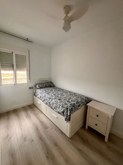 Dormitorio luminoso en CASA GIL en Aguila con cama individual, almacenaje blanco, ventilador de techo y ventana con vista al mar