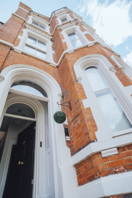 Victorian brick building entrance of Stay at Wellington Circus apartment hotel in Nottingham with white trim and hanging