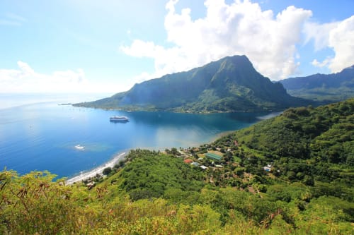 Lagon tropical avec montagnes verdoyantes et village de plage, vue de la propriété Aimehome, Polynésie française