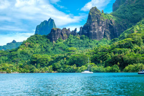 Lagon tropical aux pics verdoyants et voilier mouillé, propriété Aimehome en Polynésie française