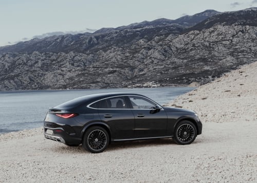 Lussuosa berlina nera parcheggiata sulla spiaggia vicino a Ravenna, Italia con montagne e fondali acquatici