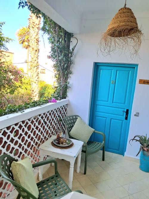 Eucalyptus balcony room at Vent Des Dunes Hotel with blue door, wicker lamp, green chairs and garden view