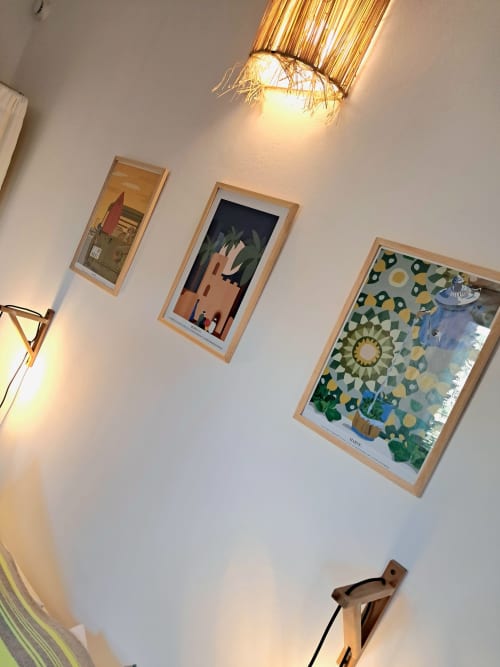 Modern artwork gallery wall in Vent Des Dunes hotel room with framed illustrations and decorative lighting fixture