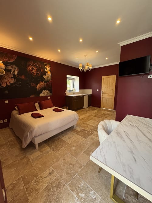 Chambre luxueuse au Domaine Des Hêtres avec murs bordeaux, deux lits, lustre et décoration élégante à Longraye