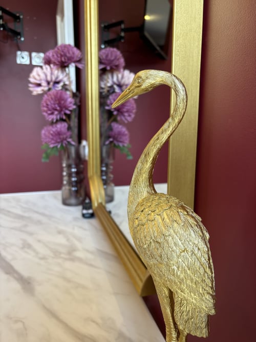 Sculpture dorée de grue se reflétant dans un miroir entouré de fleurs violettes au Domaine Des Hêtres, Longraye