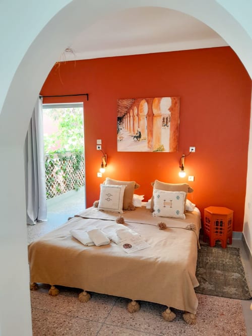 Bright orange bedroom with arched ceiling, beige bedding, pendant lights, and French doors opening to garden at Vent Des