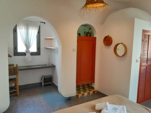 Vent Des Dunes hotel room in Essaouira features arched doorway, red door, wooden mirrors, and traditional Moroccan decor with