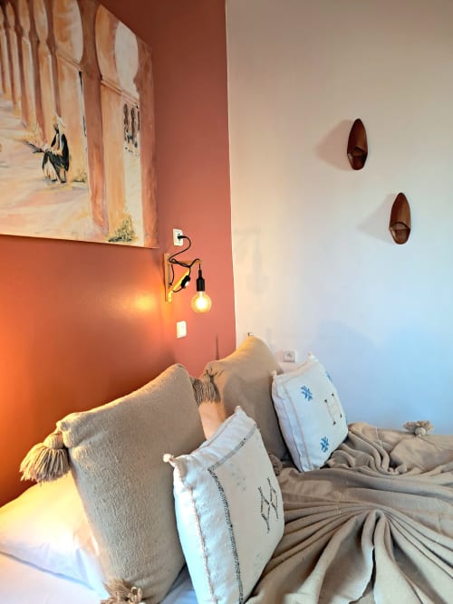 Cozy bedroom at Vent Des Dunes & Spa Essaouira with beige pillows, terracotta accent wall, pendant lamp, and decorative
