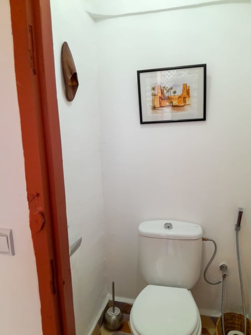 Bathroom with toilet, bidet spray, and framed desert artwork at Vent Des Dunes in Essaouira