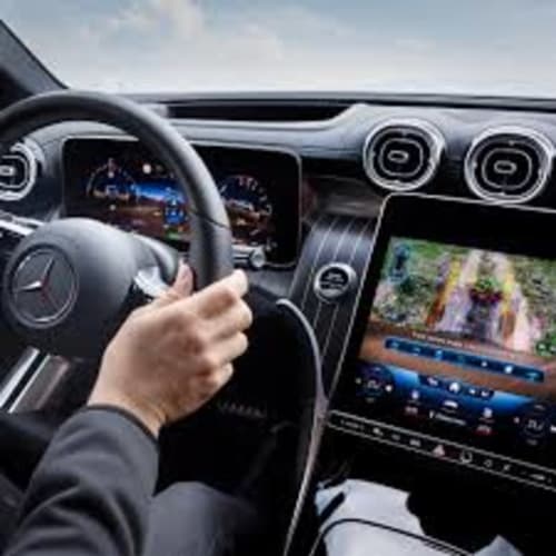 Mani del conducente sul volante di un lussuoso Mercedes con cruscotto digitale e display della mappa