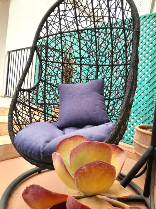 Hanging egg chair with purple cushions on terrace at Vent Des Dunes, Essaouira, with fresh fruit nearby