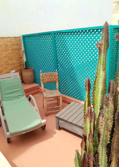 Private terrace at Vent Des Dunes & Spa, Essaouira with turquoise lattice screen, lounge chair, cacti, and wooden furniture
