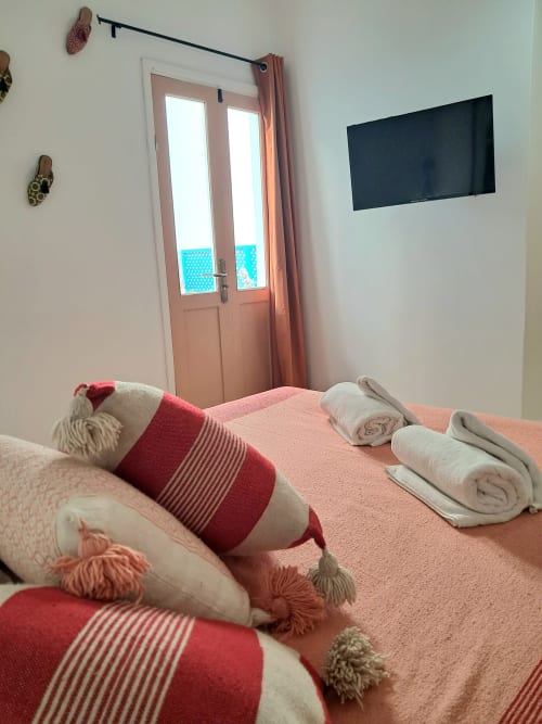 Luxury bedroom at Vent Des Dunes & Spa in Essaouira with pink bedding, flat-screen TV, and ocean view doors