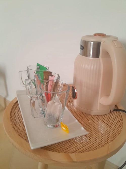 Electric kettle with glass mugs and tea sachets on wooden table at Vent Des Dunes hotel, Essaouira