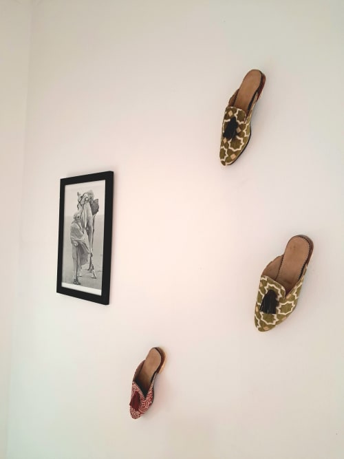 Decorative wall display at Vent Des Dunes & Spa hotel in Essaouira featuring framed artwork and three patterned mules