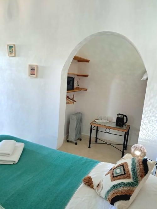 Bedroom with turquoise bedding, arched alcove with wooden shelves, desk, and radiator at Vent Des Dunes & Spa, Essaouira