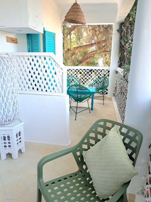 Coastal garden room with turquoise accents, wicker pendant light, and decorative chairs at Vent Des Dunes hotel, Essaouira