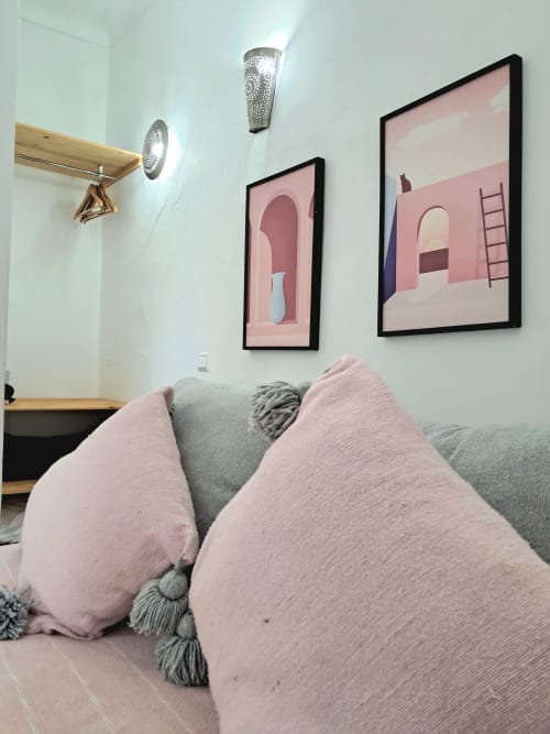 Cozy bedroom at Vent Des Dunes & Spa in Essaouira with pink pillows, decorative wall sconces, and minimalist artwork above