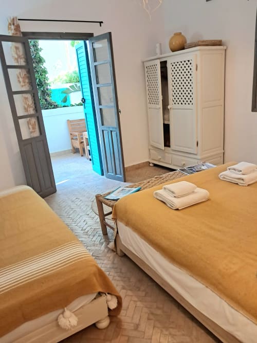 Triple bedroom with terrace at Vent Des Dunes hotel in Essaouira, featuring two beds with yellow throws and sea view door