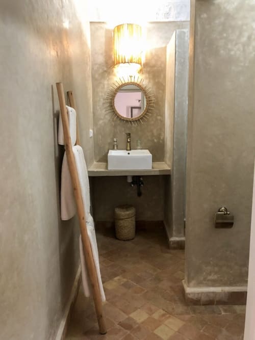 Modern bathroom in Chambre Triple Terrasse Mimosa at Vent Des Dunes & Spa, Essaouira with white sink, round mirror, and warm