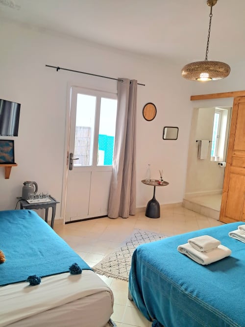 Bright triple bedroom with turquoise beds, private terrace access, and modern amenities at Vent Des Dunes hotel in Essaouira
