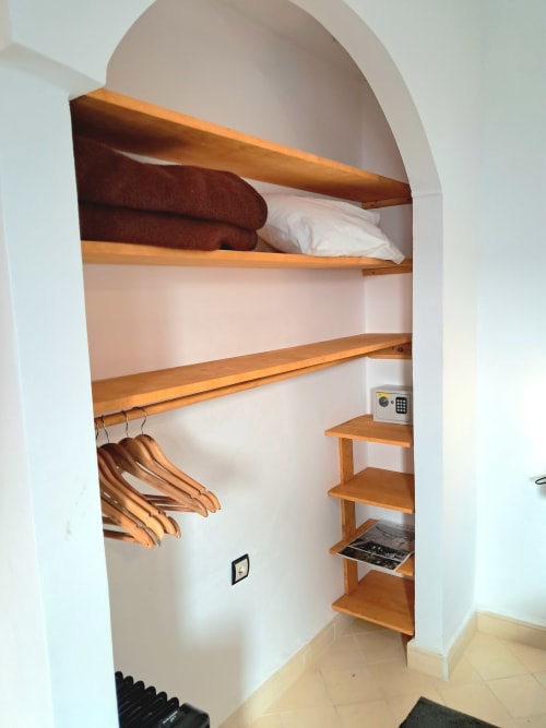 Built-in wooden shelving in a triple room at Vent Des Dunes & Spa, Essaouira, with arched white walls and storage for linens