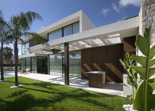 Terraza de villa moderna en Riurau Home de Calp con puertas de cristal, zona de descanso, vista a piscina privada, palmeras y césped cuidado