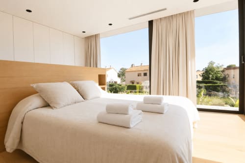 Dormitorio moderno en Villa Ona de Riurau Home, Calp, con cama de madera, ropa blanca y vistas al paisaje y zona de piscina