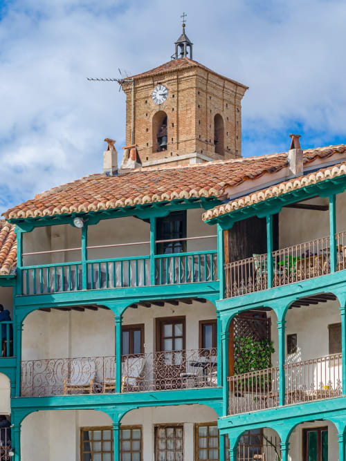 Fachada colonial turquesa de Casa Rural La Herrería con torre de reloj en Colmenar de Oreja