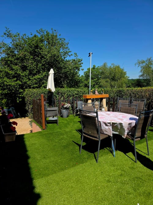 Gartenterrasse von La Maison de la Colline mit Esstischen, Sonnenschirm und grünem Rasen in Vers, Frankreich