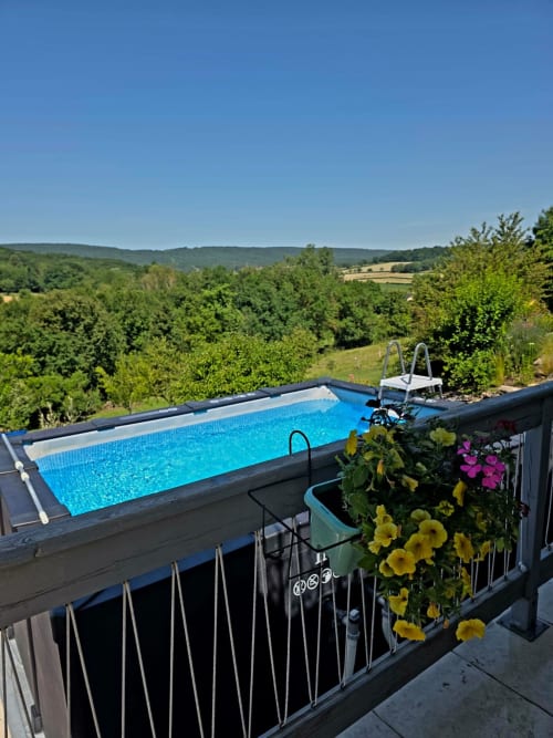 Erhöhter Swimmingpool mit blauem Wasser mit Blick auf üppig grüne Täler in La Maison de la Colline, Vers, Frankreich